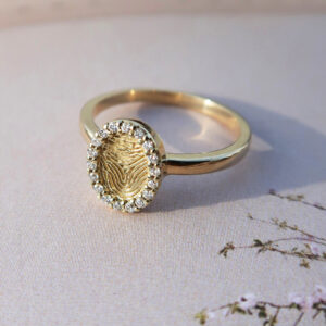 Deze ring van het merk Minioro bestaat uit 14 karaats goud en heeft een bedel waarin een vingerafdruk of gravering kan worden gezet. Zo ontstaat een elegant en persoonlijk aandenken vol betekenis. Deze is afgewerkt met prachtige diamanten