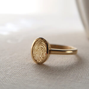 Deze ring van het merk Minioro bestaat uit 14 karaats goud en heeft een bedel waarin een vingerafdruk of gravering kan worden gezet. Zo ontstaat een elegant en persoonlijk aandenken vol betekenis.